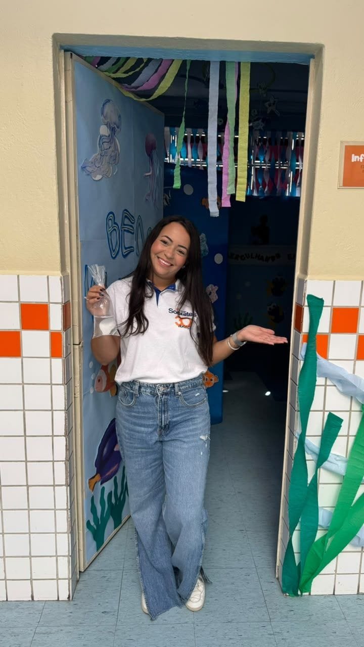 Educadora do Colégio Sócrates na porta da sala decorada com algas e fitas